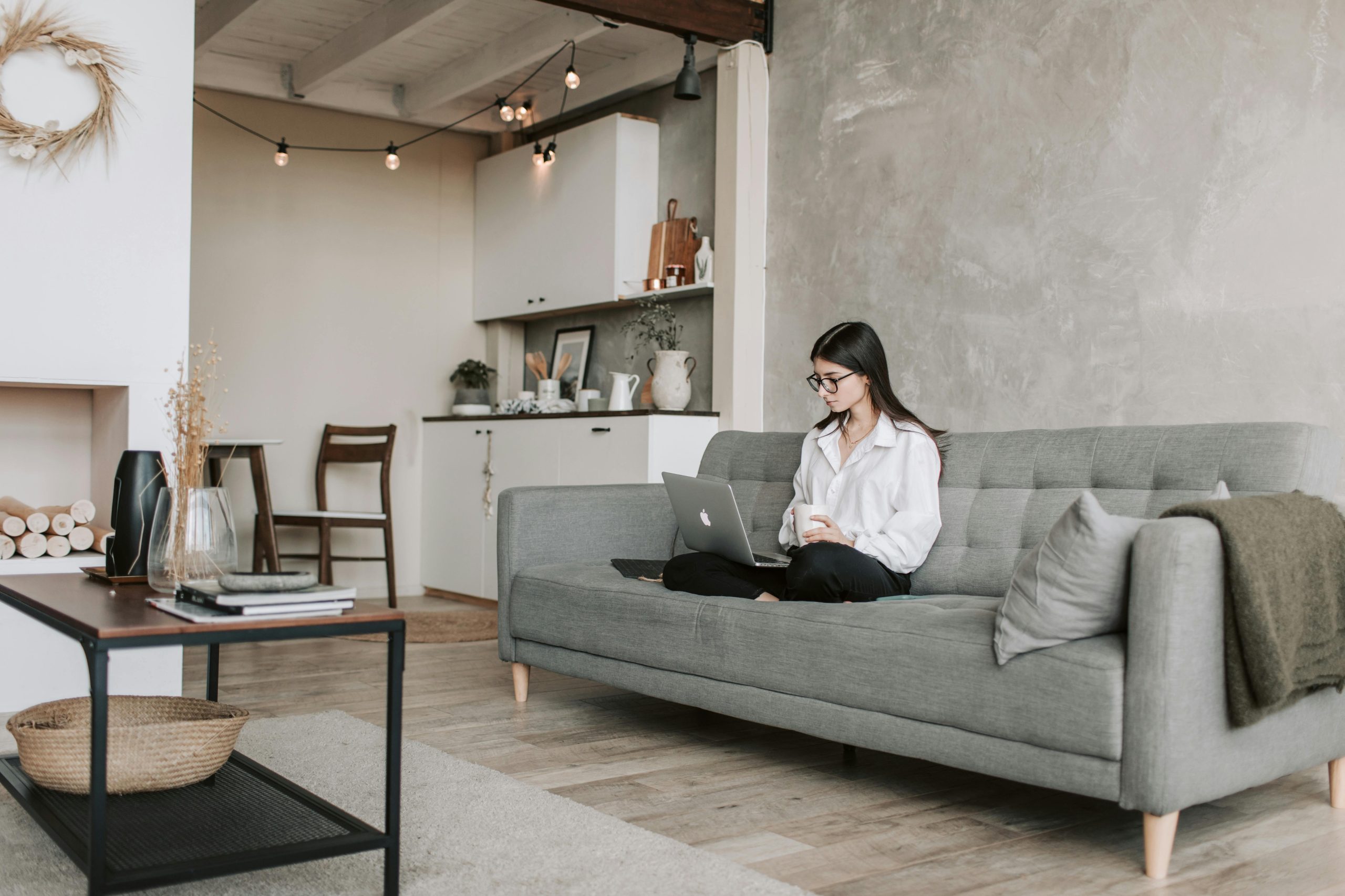 Woman comfortably working on a laptop in a stylish, cozy living room setting.